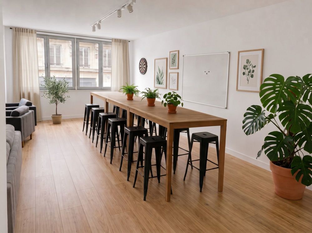 Table haute en bois et tabourets noirs dans la salle de pause, tableau blanc au mur