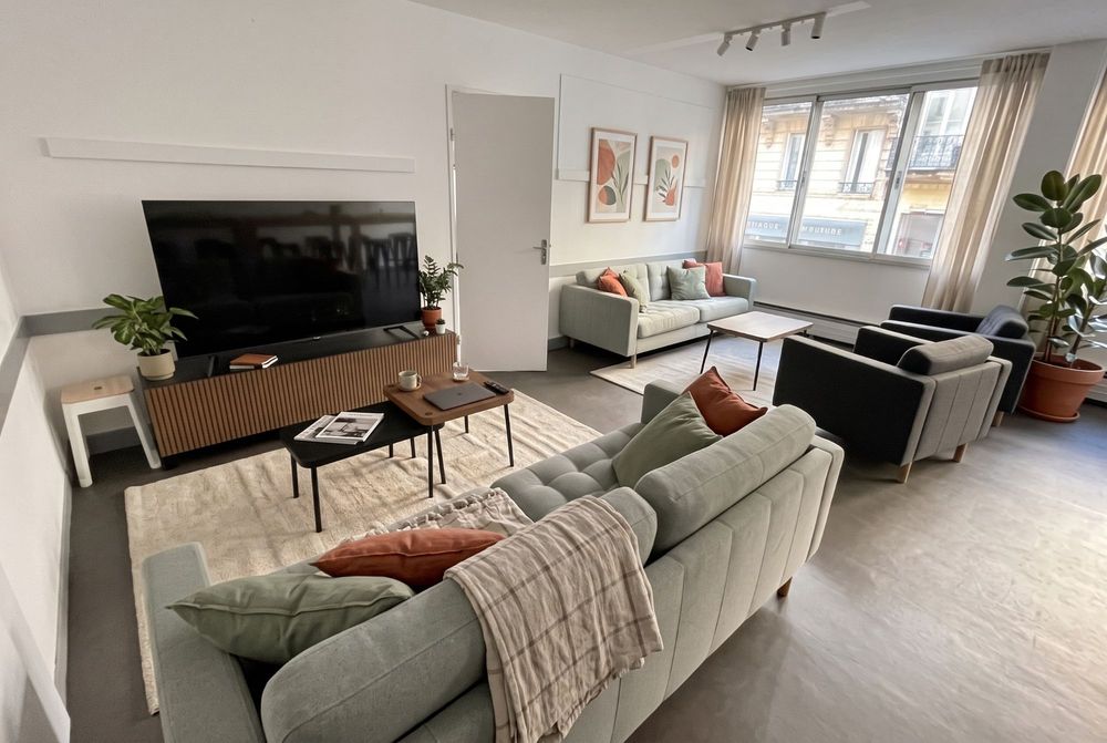 Coin salon avec canapés, fauteuils, tapis et grand écran